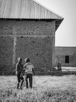 Two children playing outside a brick building in a rural area of Burundi.