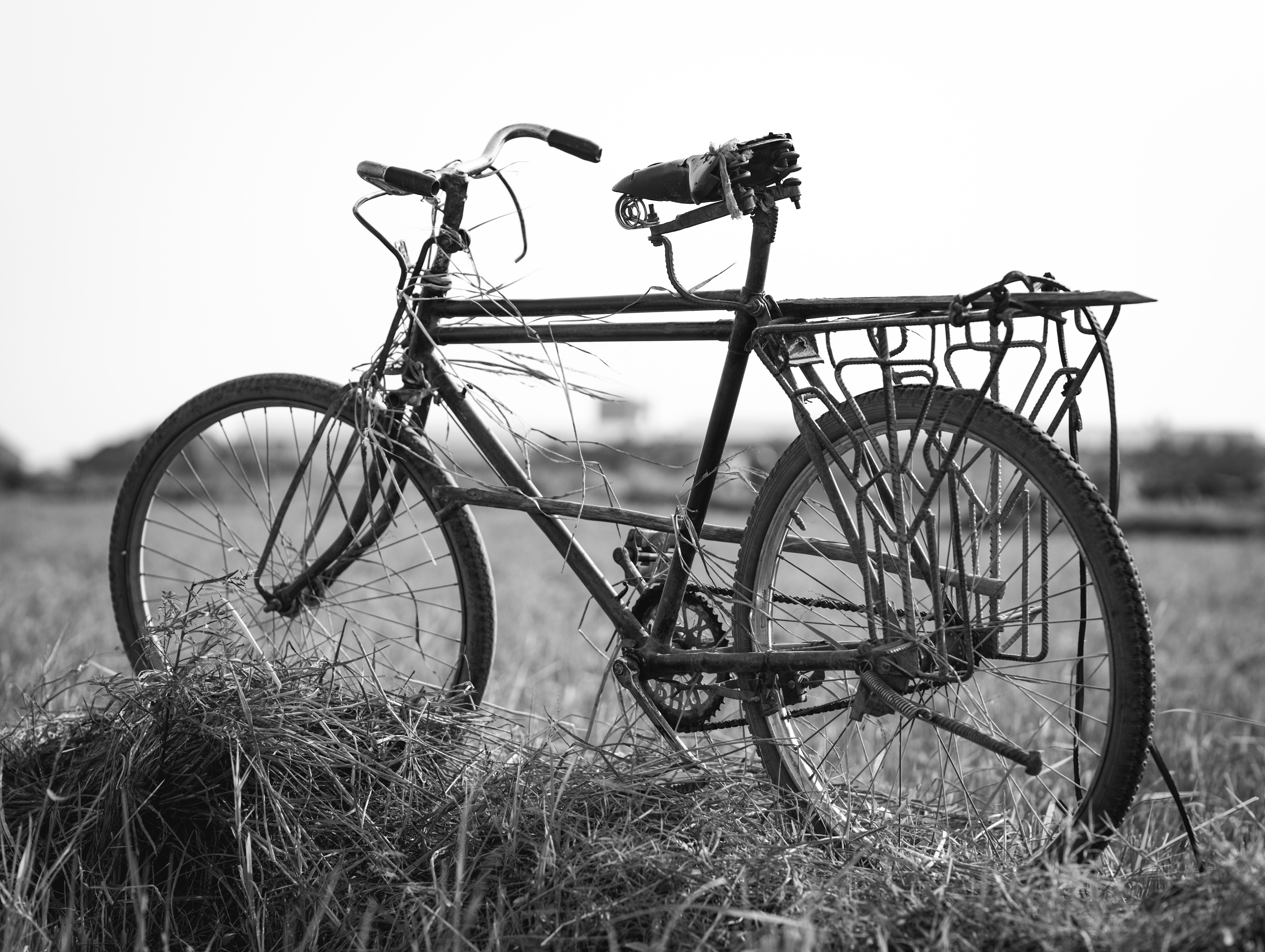 Black and white image of an old bicycle in a grassy field in Burundi.