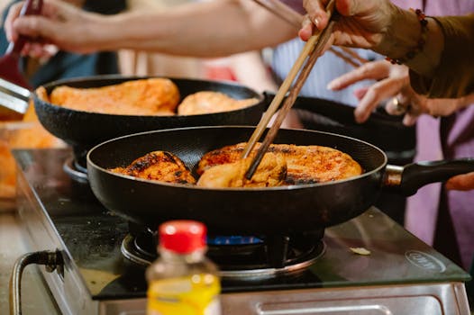 Hands cooking in a kitchen, frying delicious food on stovetop pans, showcasing culinary skills.