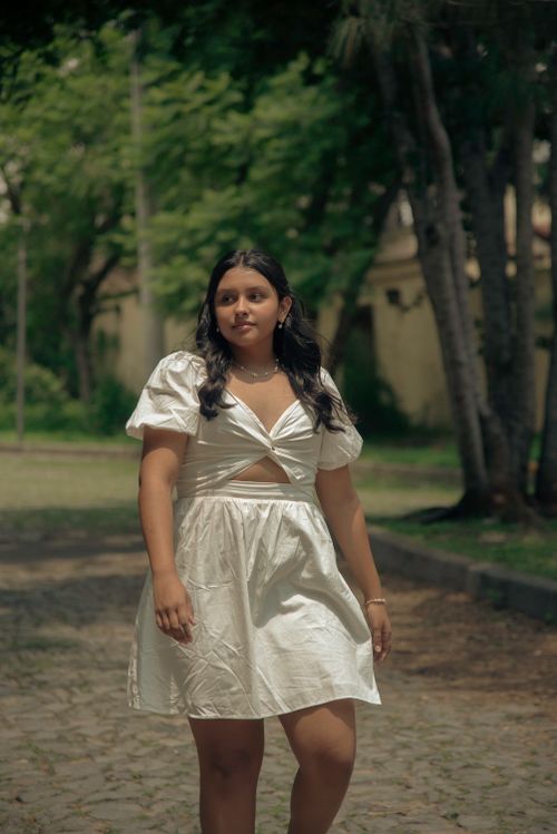 Free A young woman walks confidently along a tree-lined path during a sunny summer day. Stock Photo