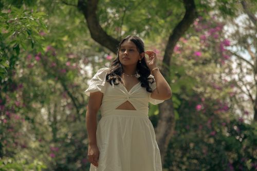Free A serene woman in a white dress amidst vibrant blossoms in a peaceful natural setting. Stock Photo