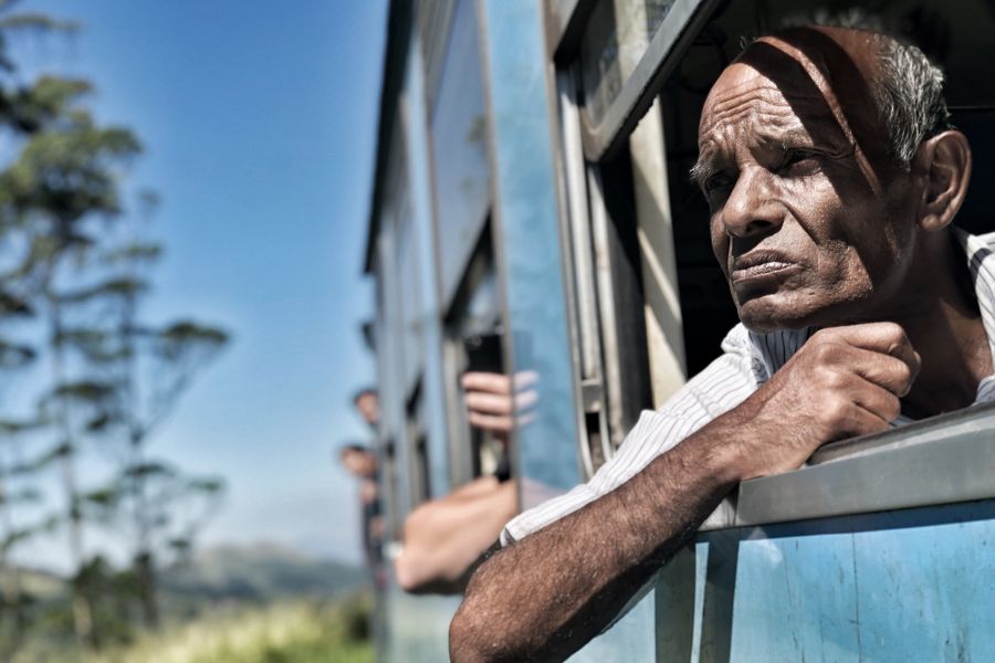 Thoughtful older man gazing from a train window during a journey in Sri Lanka.
