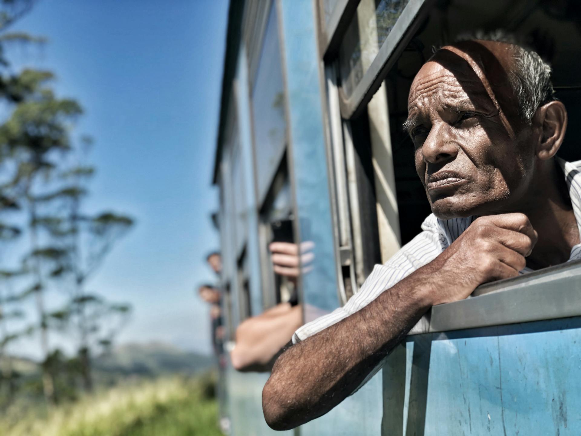 Thoughtful older man gazing from a train window during a journey in Sri Lanka.