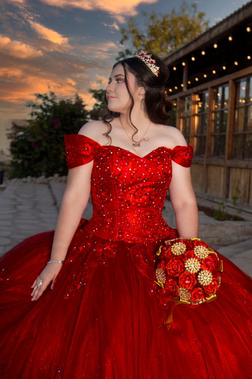 Free Beautiful young woman in a red quinceañera dress holding a bouquet during sunset. Stock Photo