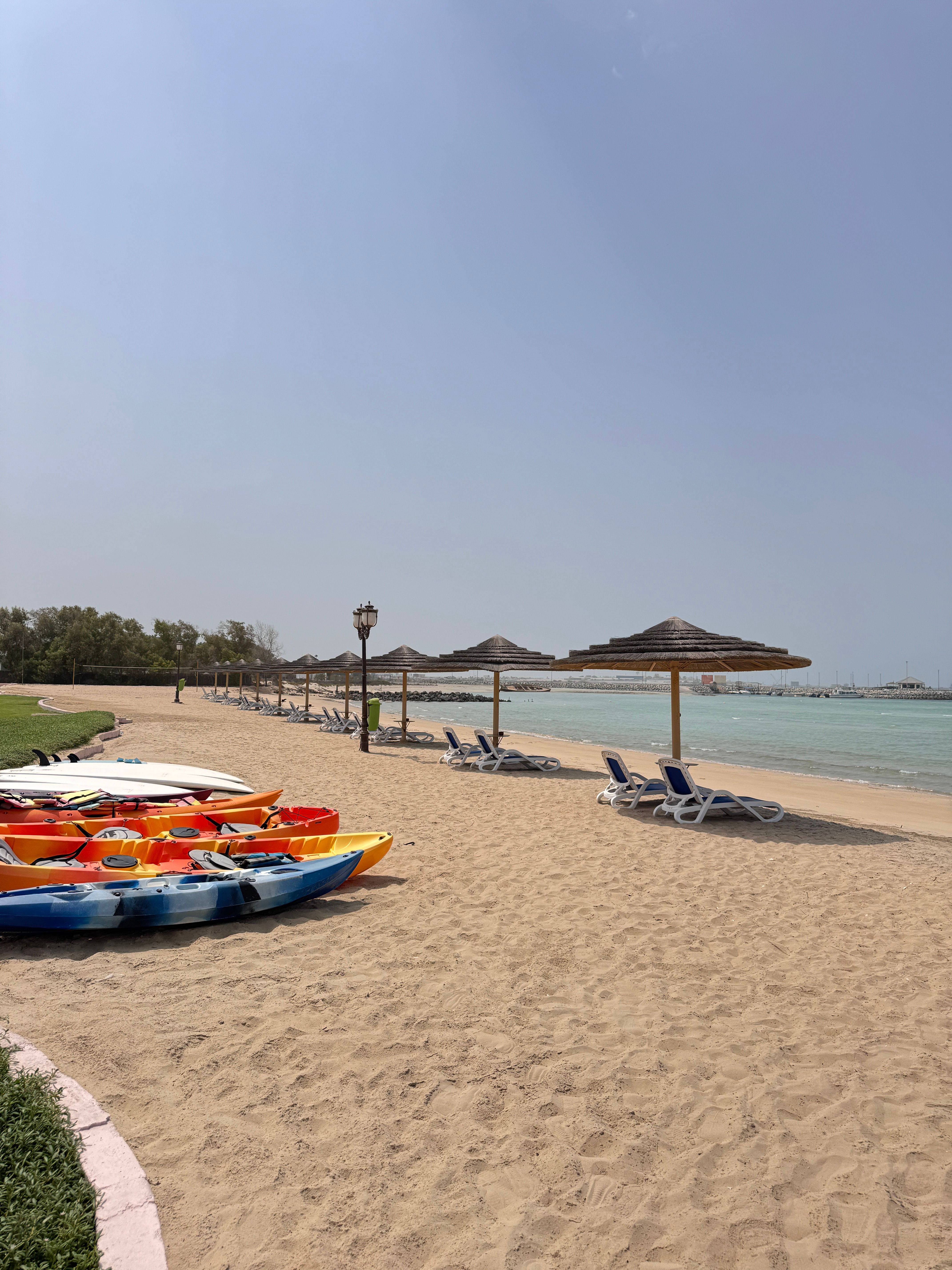 Kayaks and beach loungers arranged along a calm shoreline
