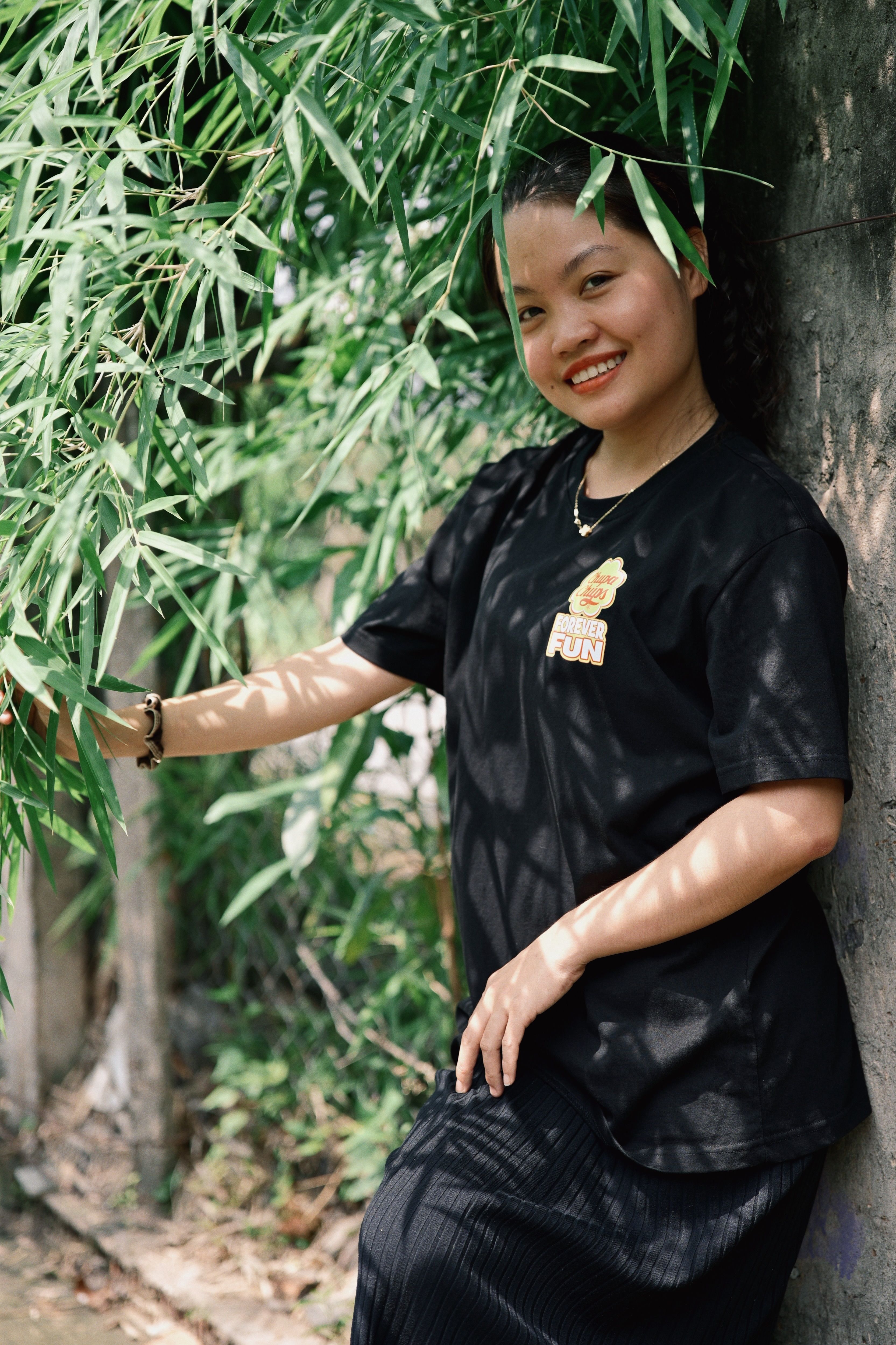 Smiling Woman Posing Outdoors Amidst Greenery · Free Stock Photo
