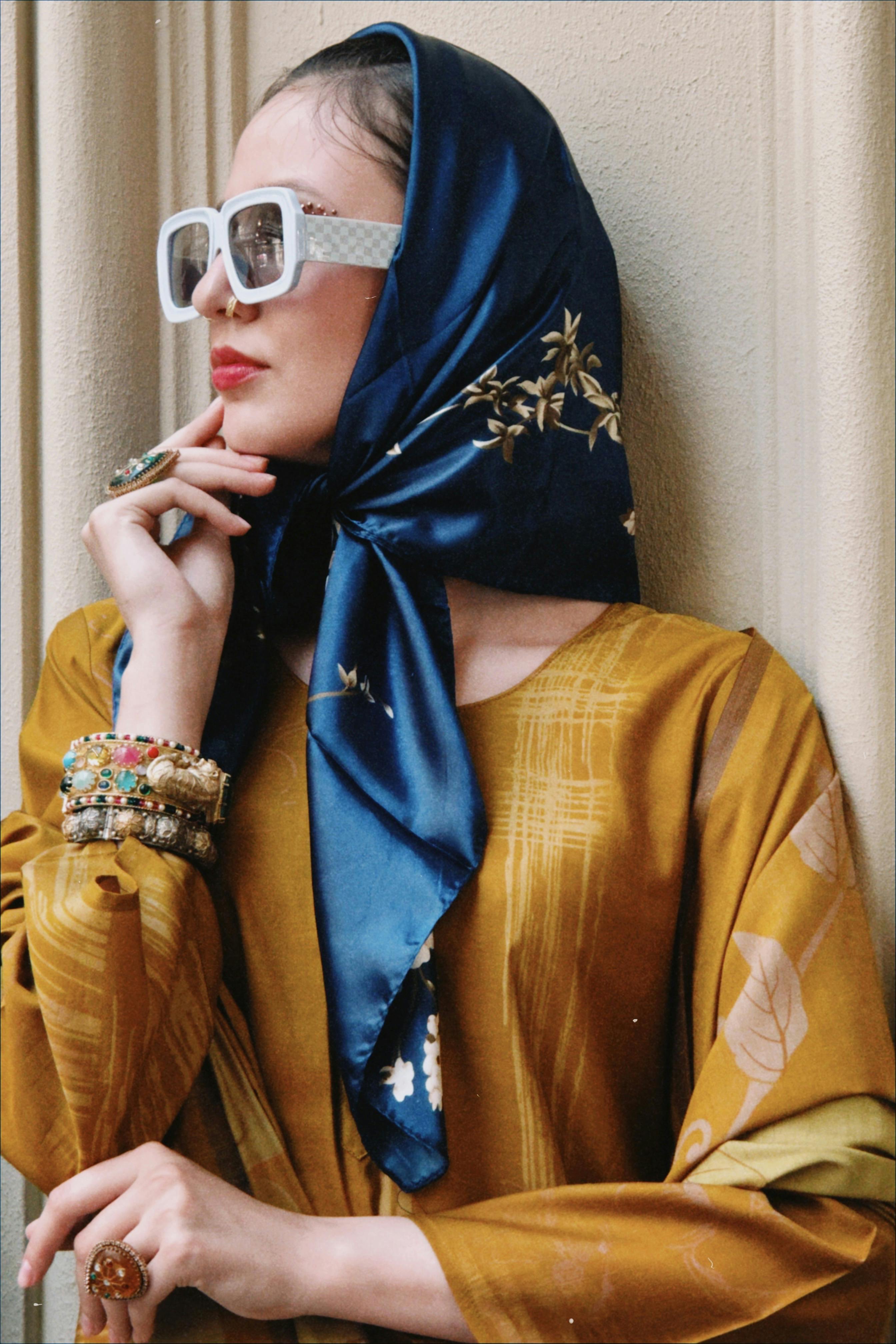 Stylish woman in a blue scarf and sunglasses, embodying classic fashion.