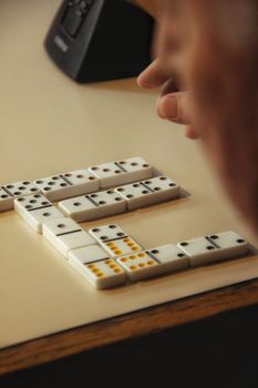 A close-up of a hand playing a domino game on a table indoors, creating an inviting and strategic atmosphere.