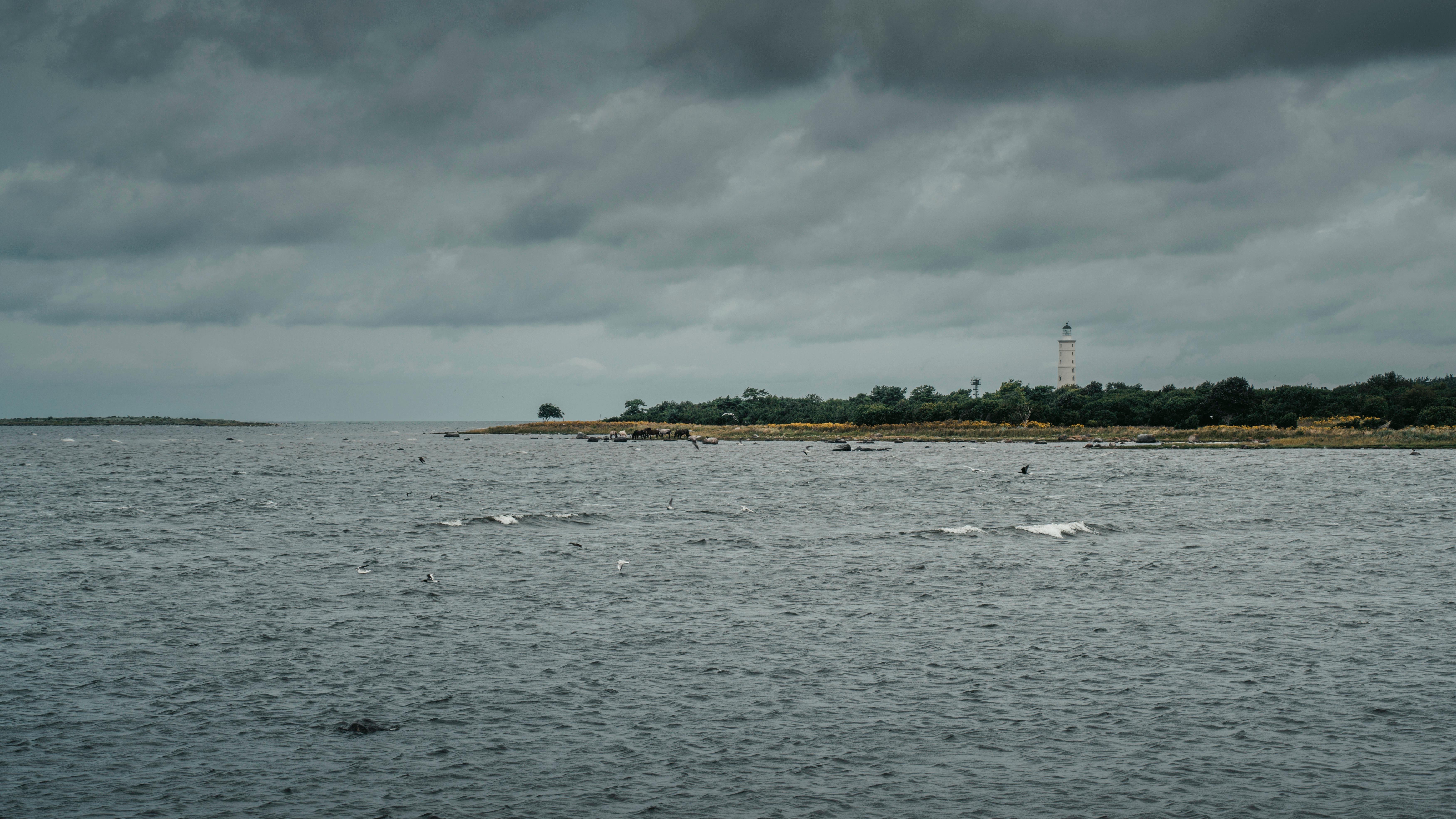 Dramatic view of Vilsandi coastline and lighthouse under a cloudy sky.