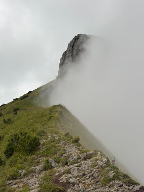 Free Rugged mountain path leading into clouds beside imposing rock formation, perfect for adventure lovers. Stock Photo
