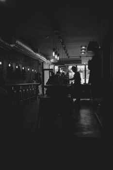 Silhouette of a person inside a dimly lit café, highlighting a cozy and intimate atmosphere.