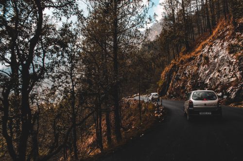 Free Cars driving on a winding mountain road through an autumn forest with scenic views. Stock Photo