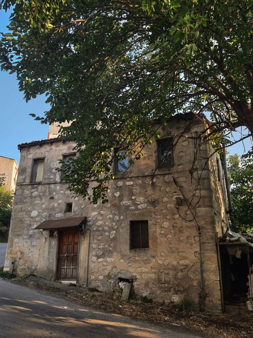 Free A rustic stone building surrounded by lush greenery, evoking a serene rural ambiance. Stock Photo