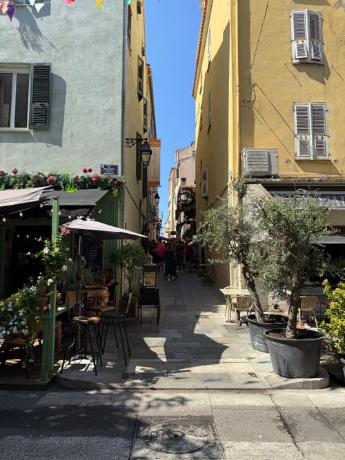 Free Scenic alleyway in Ajaccio, showcasing colorful architecture and outdoor cafes in sunny Corse, France. Stock Photo
