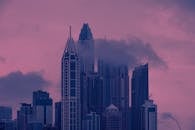 迷人的城市景观中，摩天大楼与云彩在生动的粉红色和紫色日落映衬下格外美丽