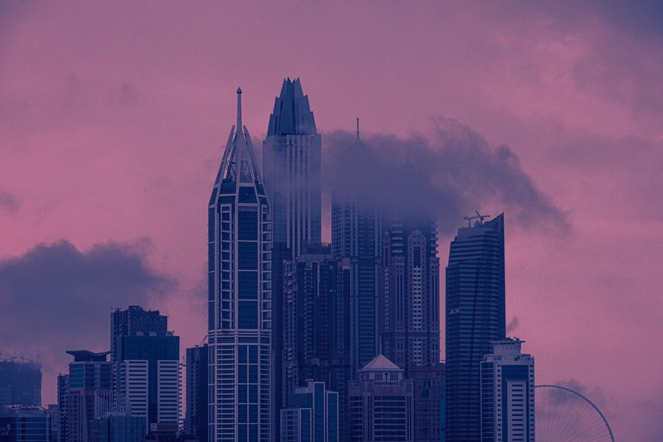 Captivating cityscape with skyscrapers and clouds during a vivid pink and purple sunset.