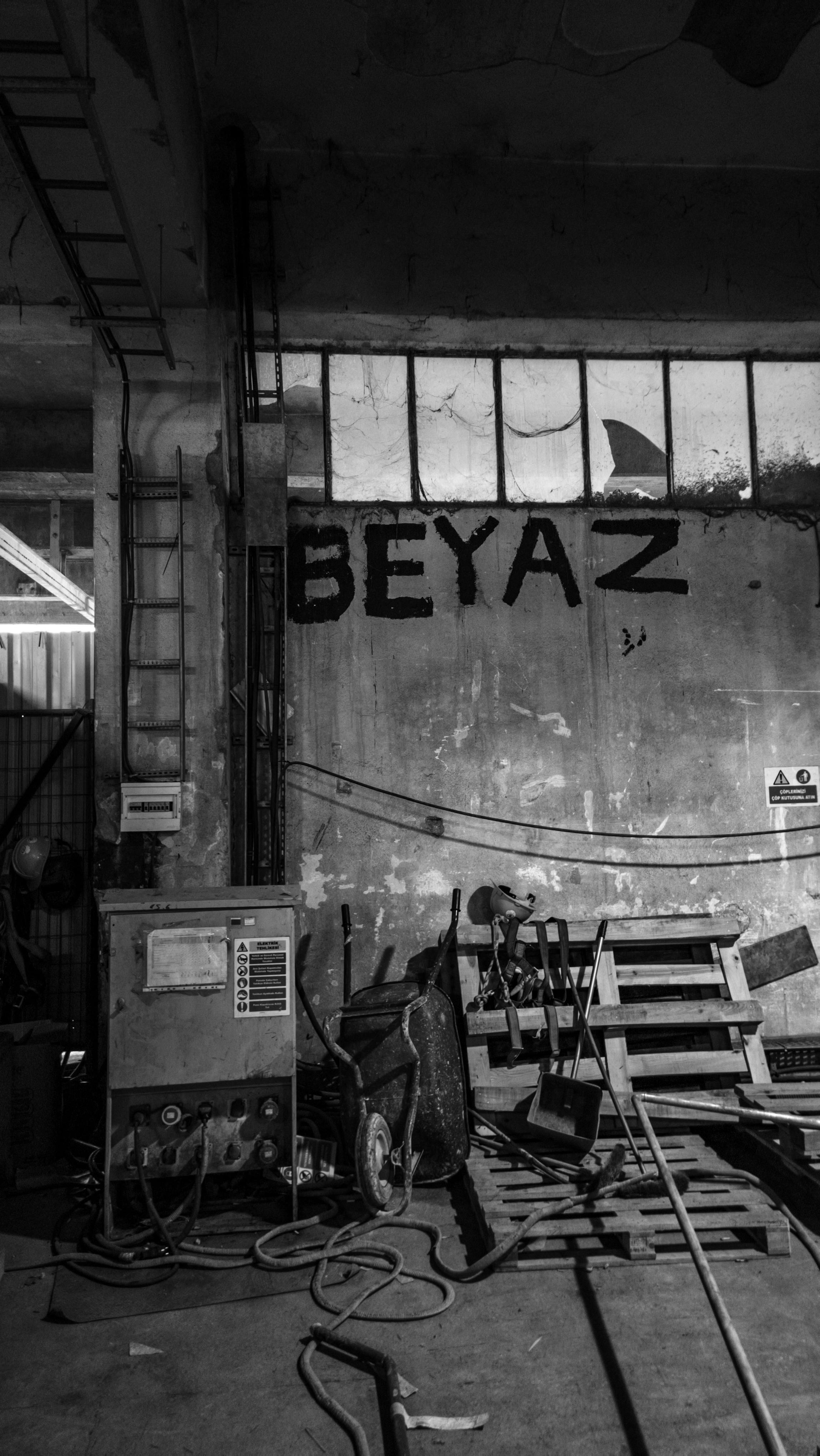 Monochrome photo of an industrial warehouse interior with graffiti art and scattered tools.
