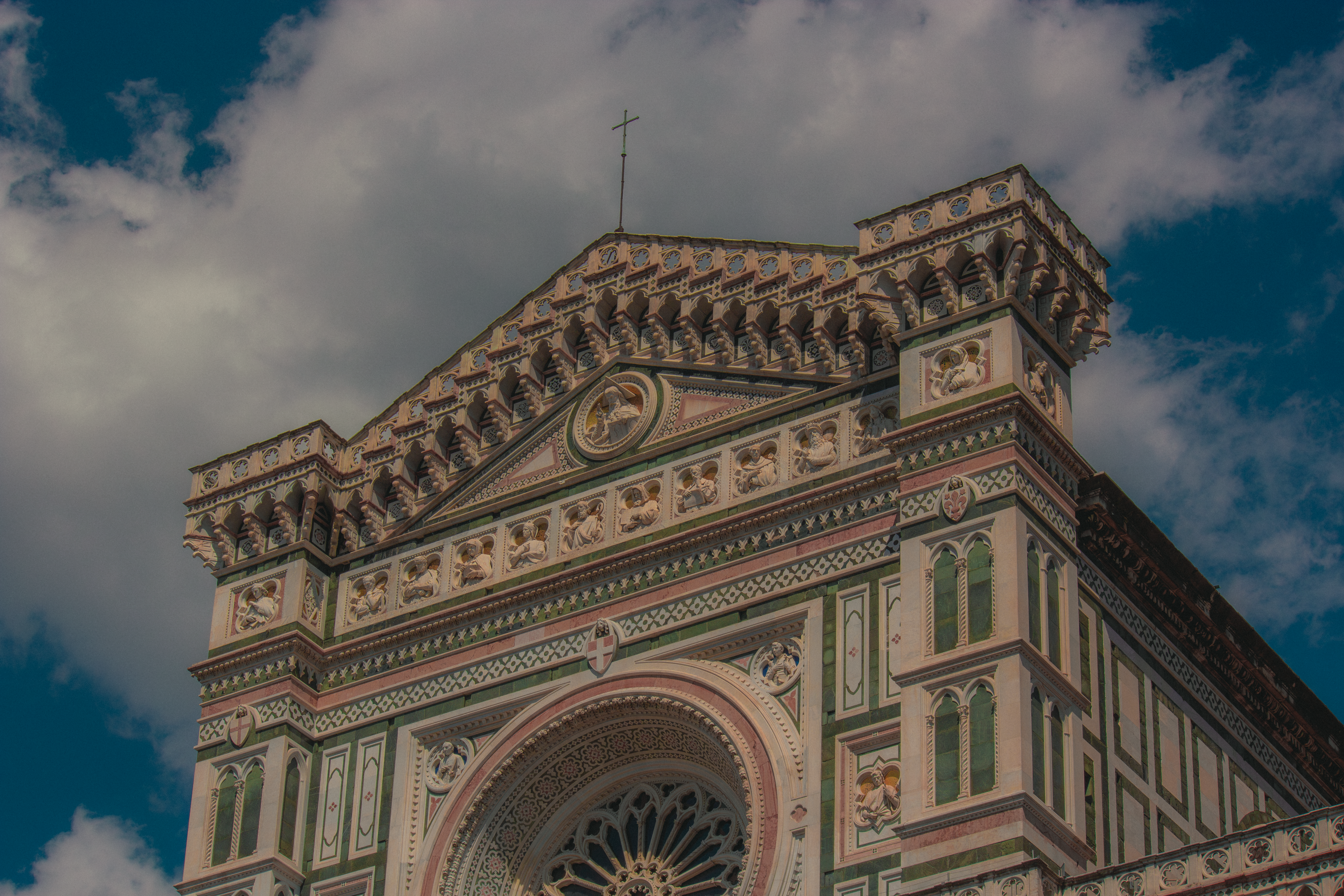 Close-up of Florence Cathedral's ornate facade with intricate designs under a blue sky.
