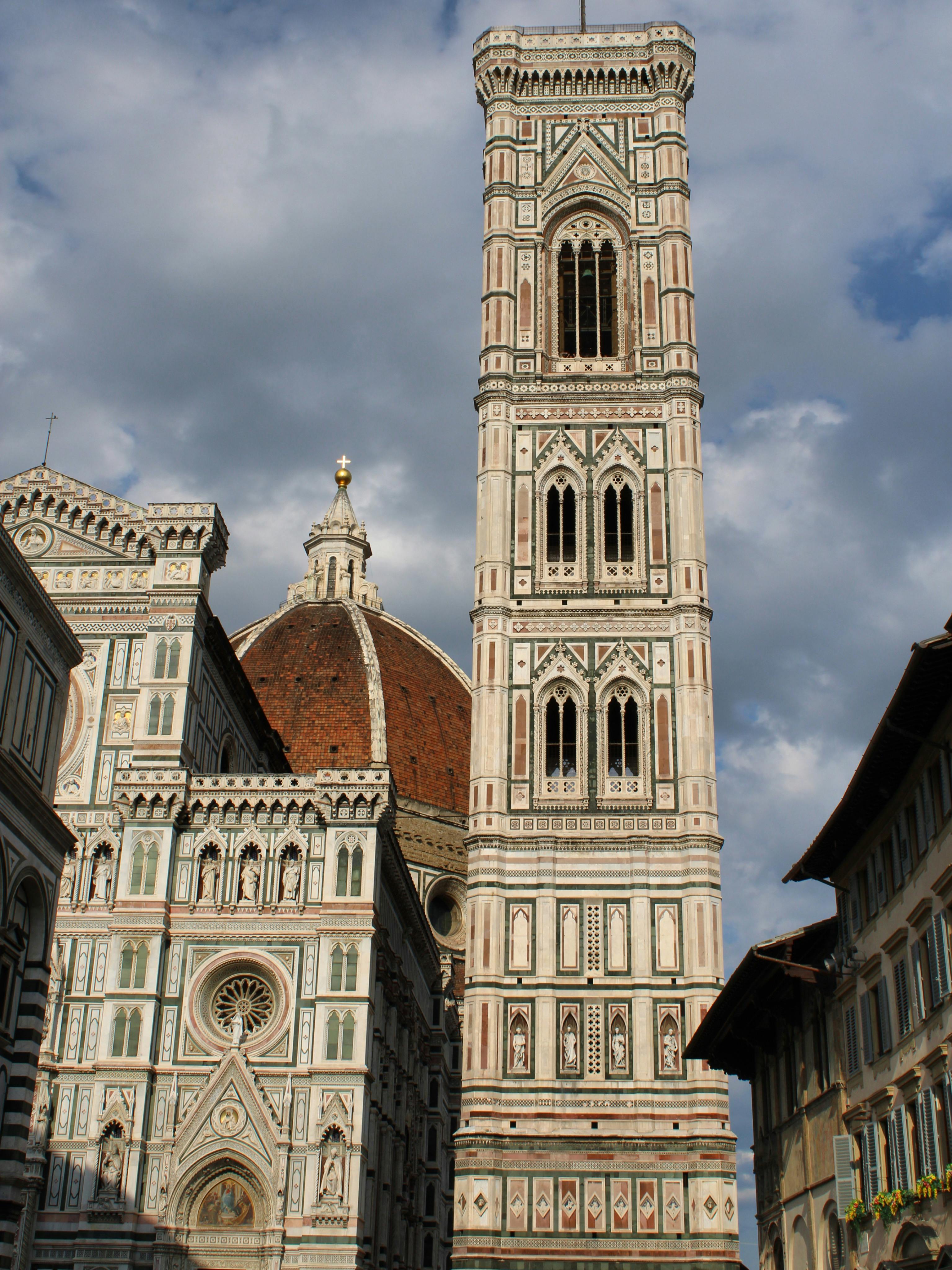 Iconic view of Giotto's Campanile and Florence Cathedral under a cloudy sky.