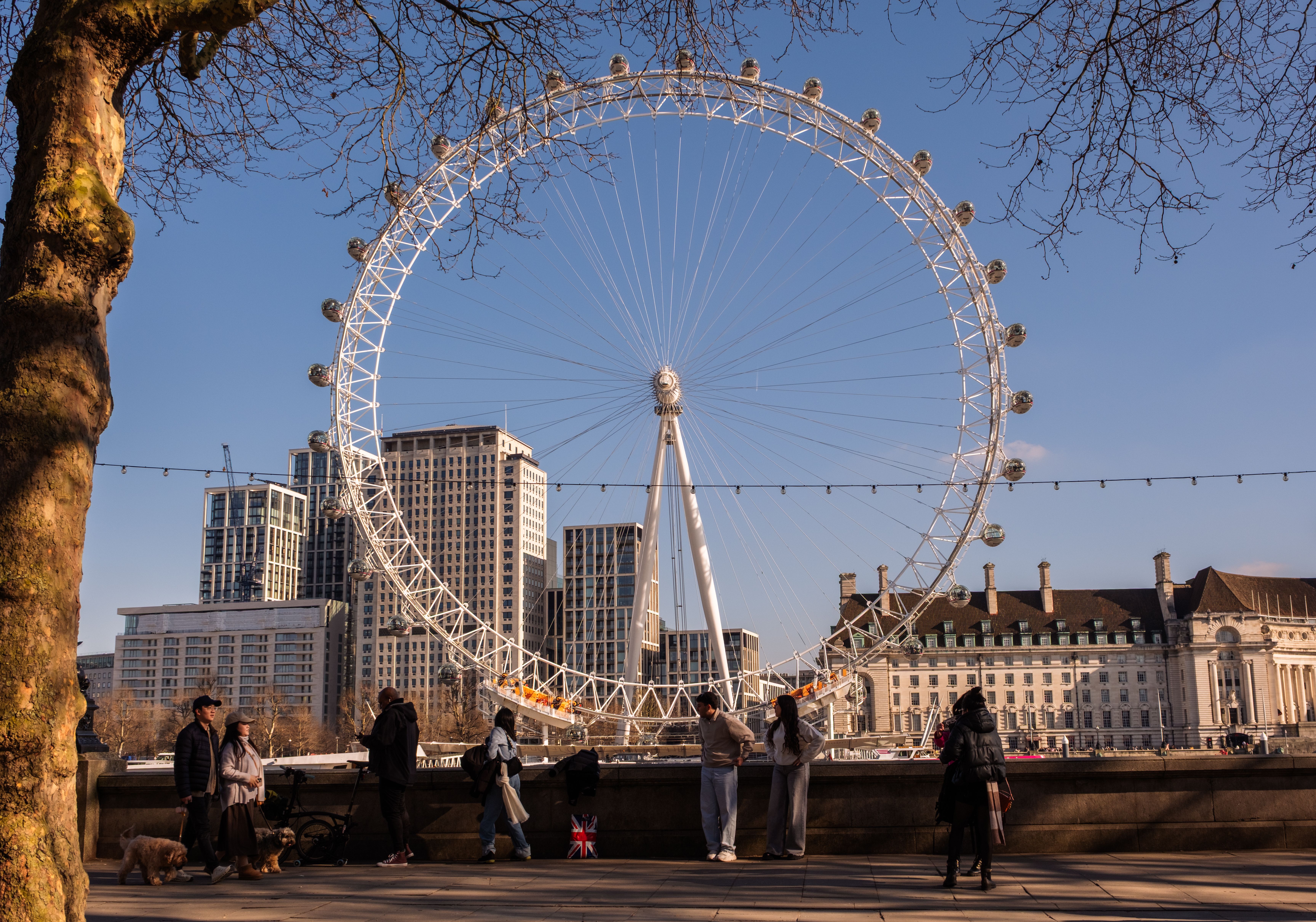 Visitors strolling near the London Eye on a sunny day, with a vivid view of the cityscape.