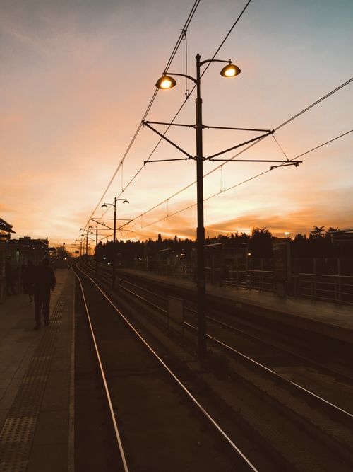 Free Peaceful train station view at sunset with empty tracks creating a calm atmosphere. Stock Photo