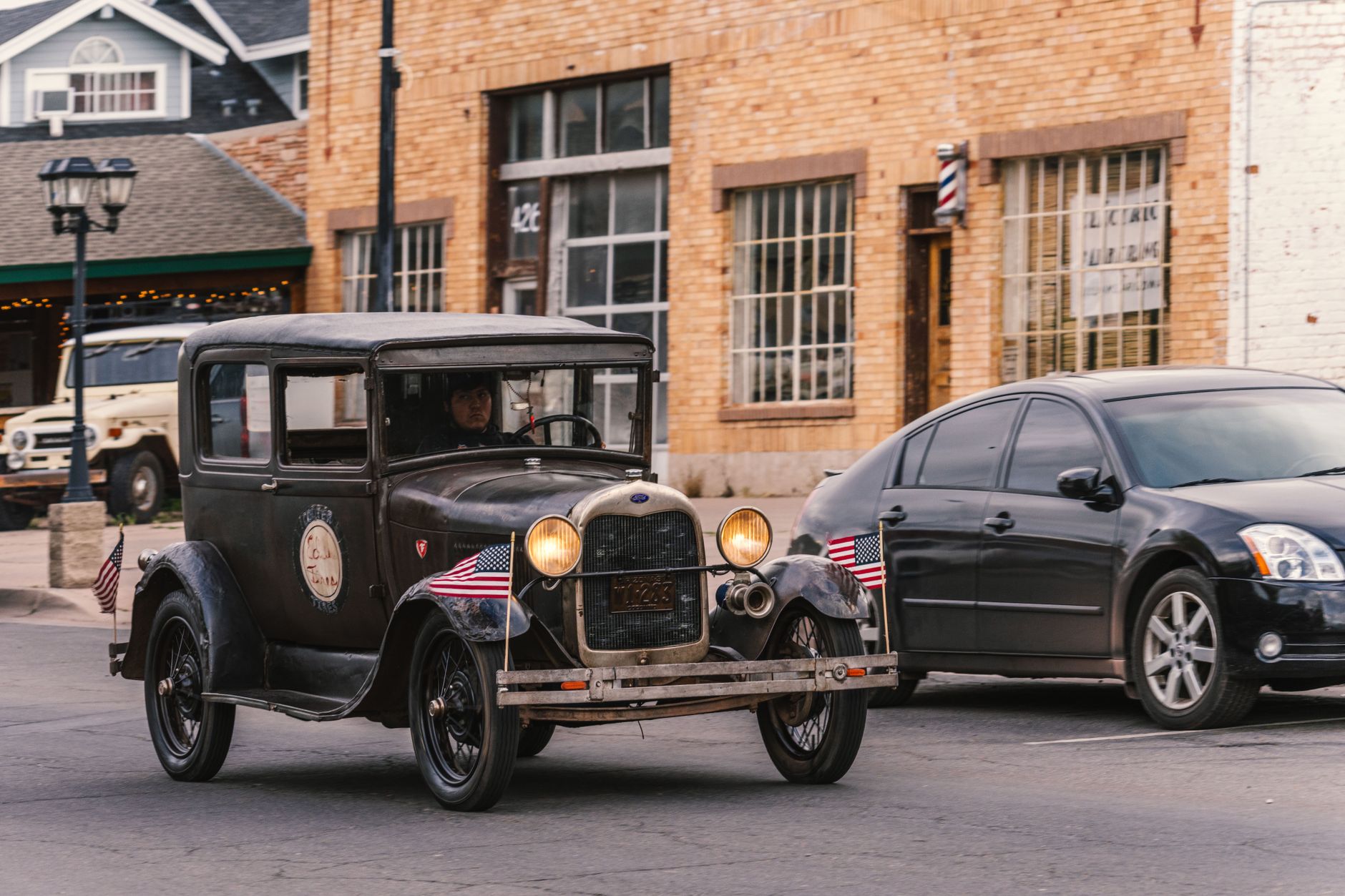 Vintage Ford with American flags driving on historic Route 66 in Williams, Arizona.