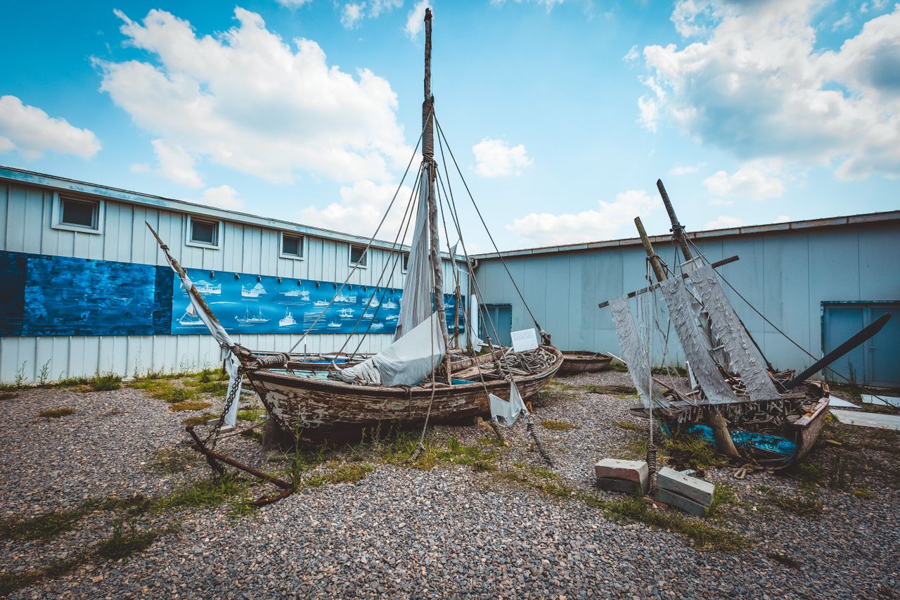old wooden sailboats in an outdoor yard against a blue sky showcasing