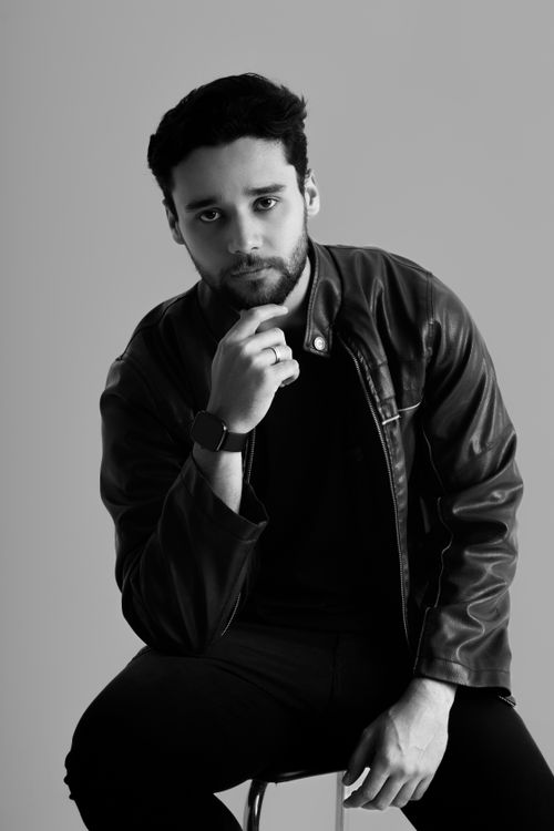 Free Black and white portrait of a young man in a leather jacket seated in a thoughtful pose. Stock Photo