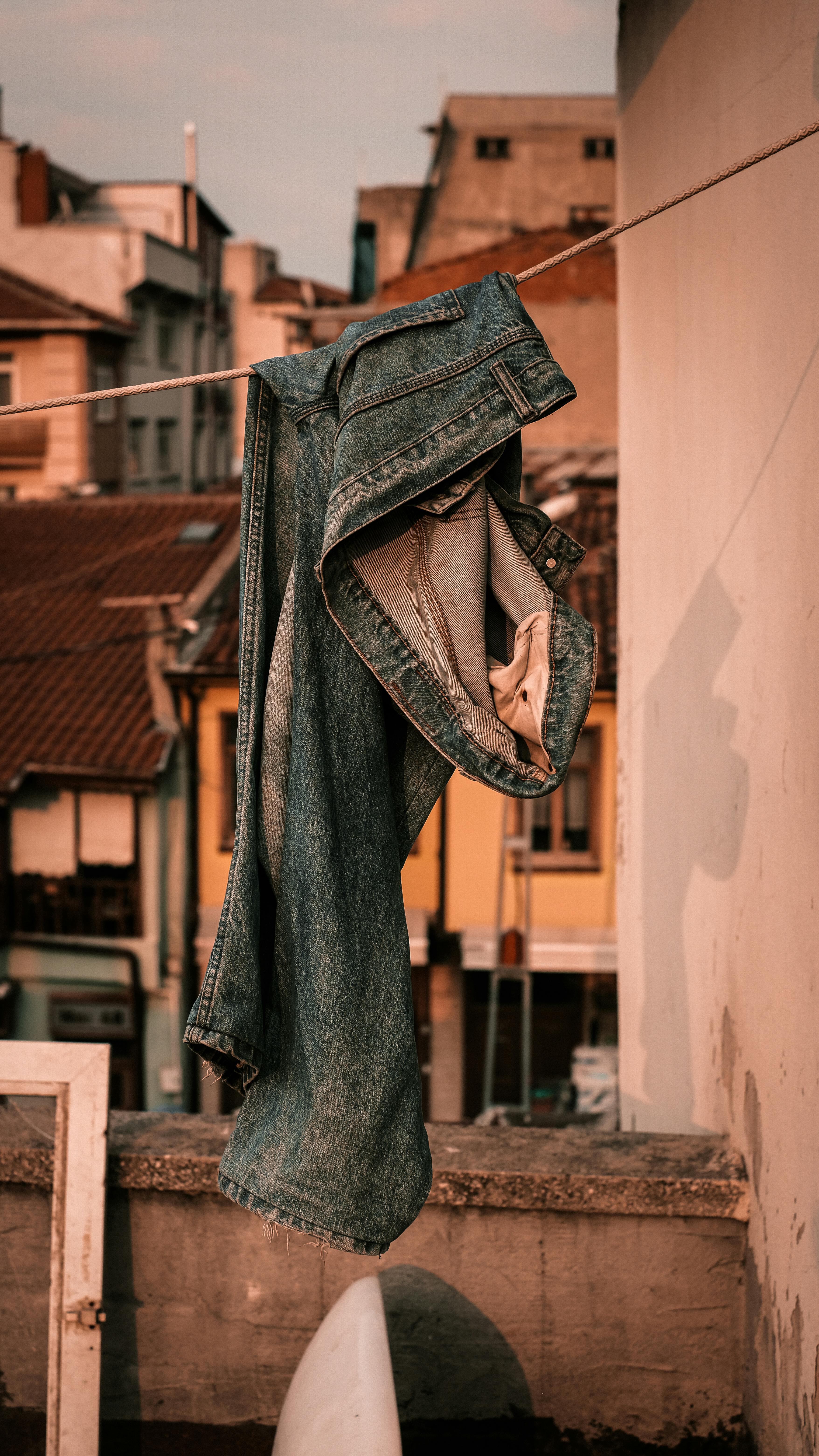Kostenlos Blaue Jeans hängen auf einer Leine vor dem Hintergrund einer rustikalen Dachterrasse in Bursa, Türkei. Stock-Foto