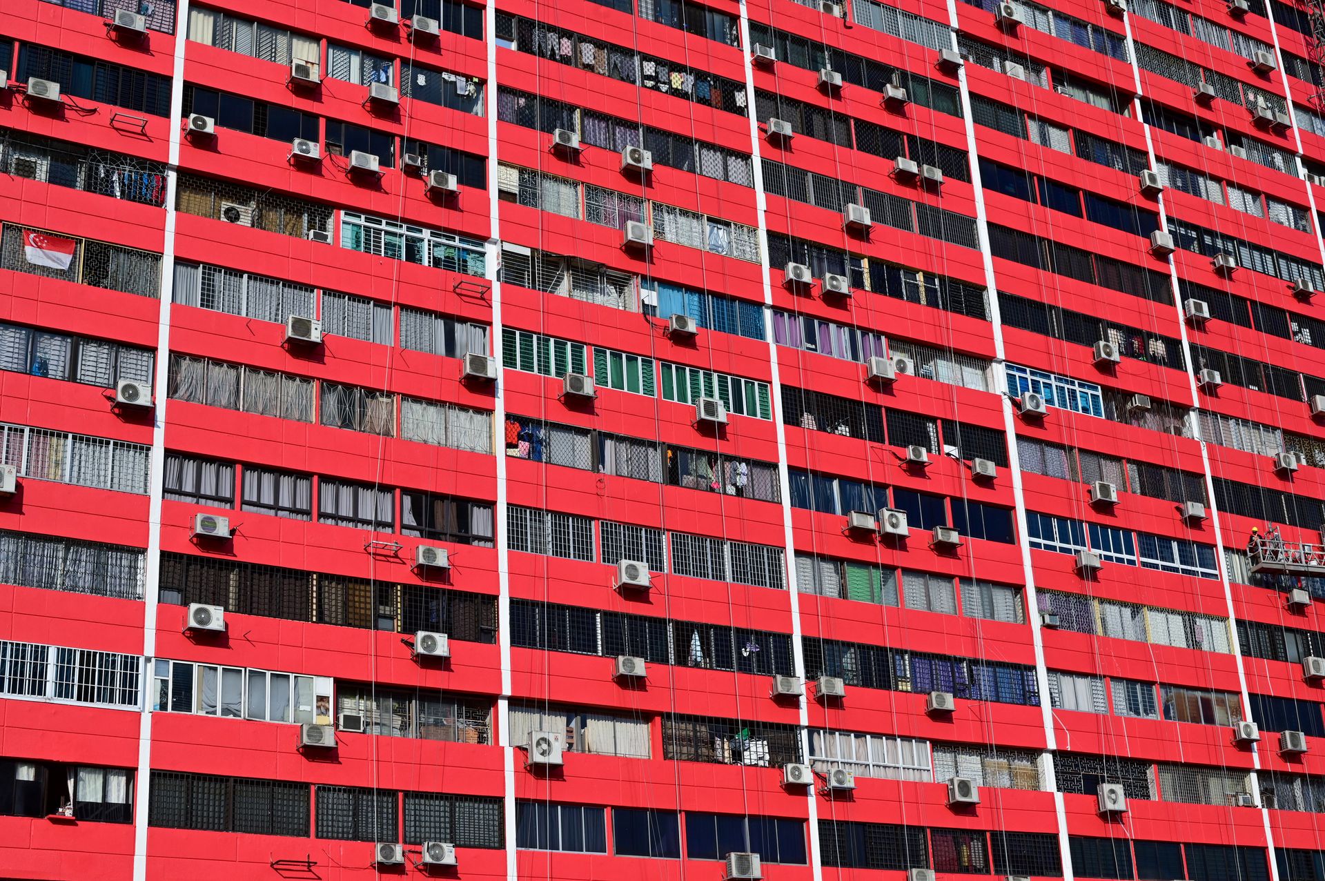Colorful residential building facade in Singapore's Chinatown with air conditioners and varied windows.
