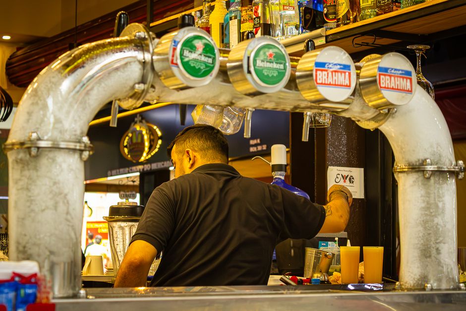 A bartender prepares and serves drinks at a bustling bar with a vintage draft beer system.