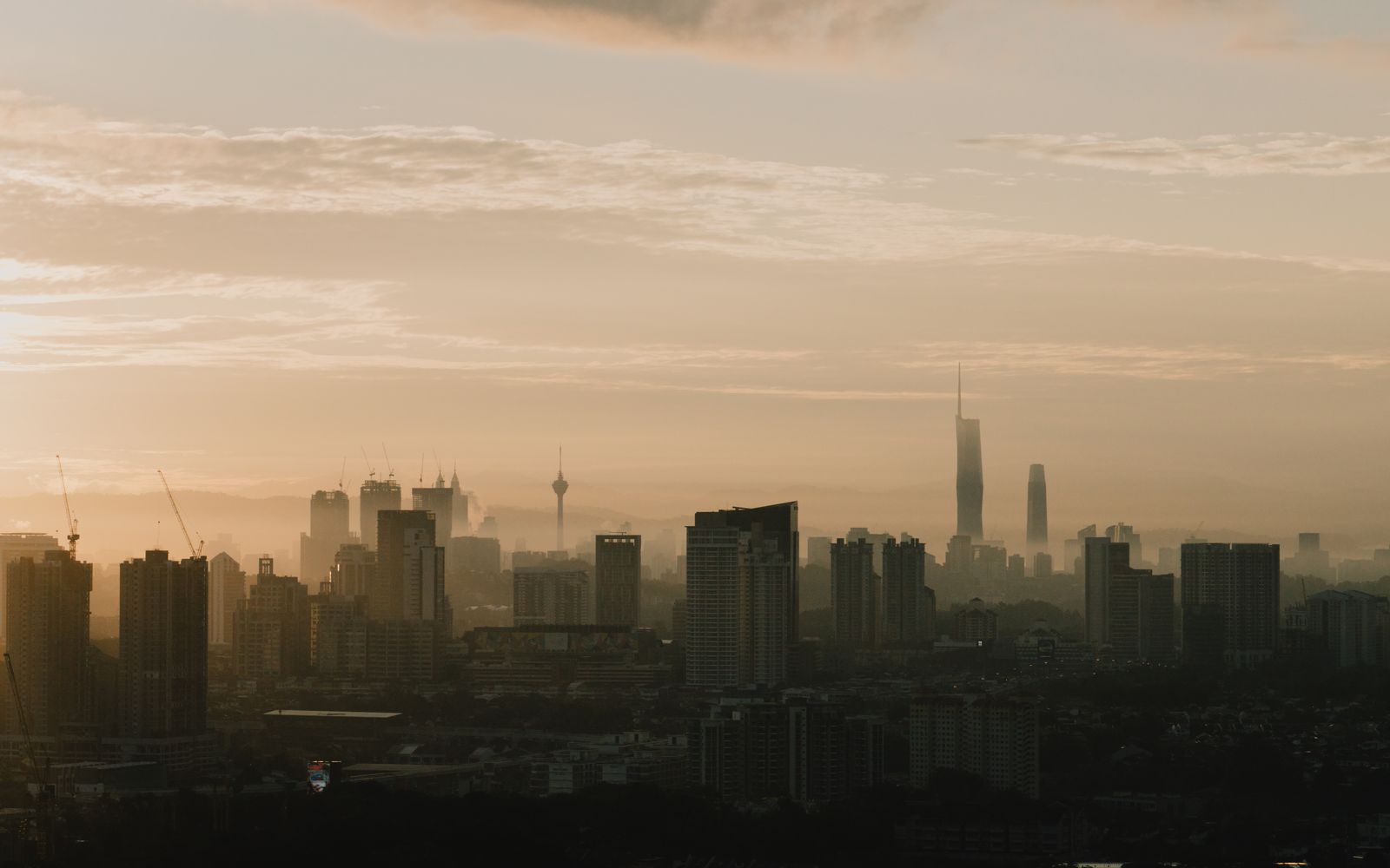 Kuala Lumpur skyline in silhouette under a misty sunrise sky