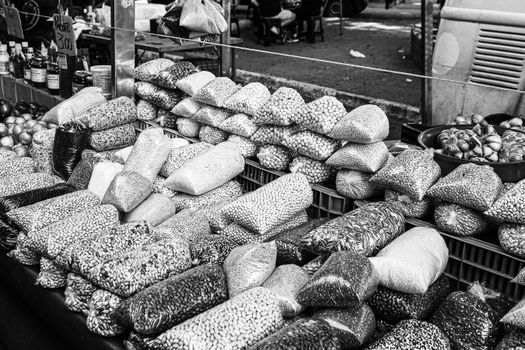 Black and white image of a market stall with various bagged grains and nuts on display. Perfect for culinary and cultural themes.