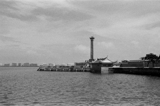Monochrome view of a riverfront featuring a traditional tower and architectural structures.
