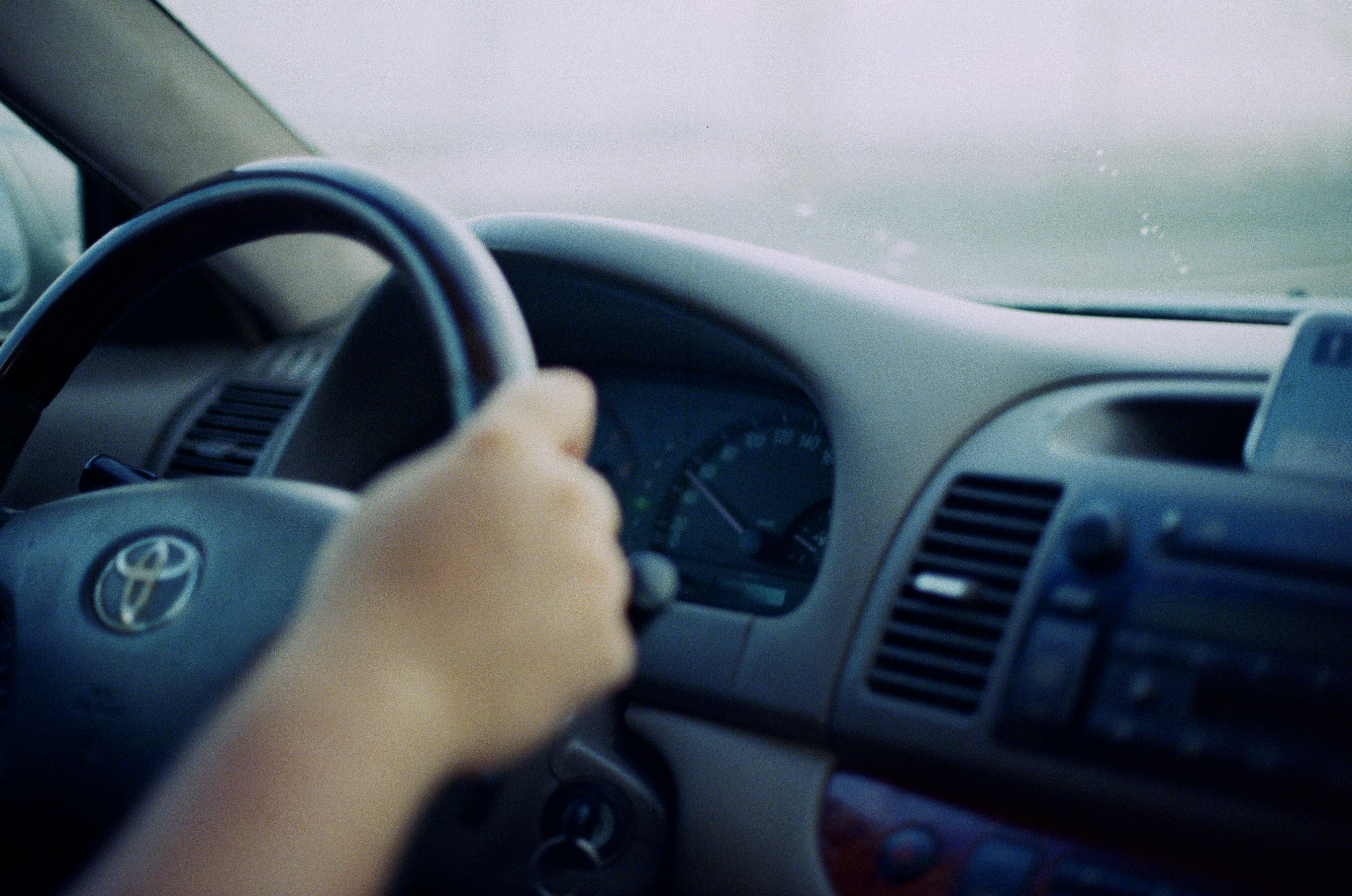 Free Driver's hand on a car steering wheel inside a vehicle, emphasizing in-car perspective. Stock Photo