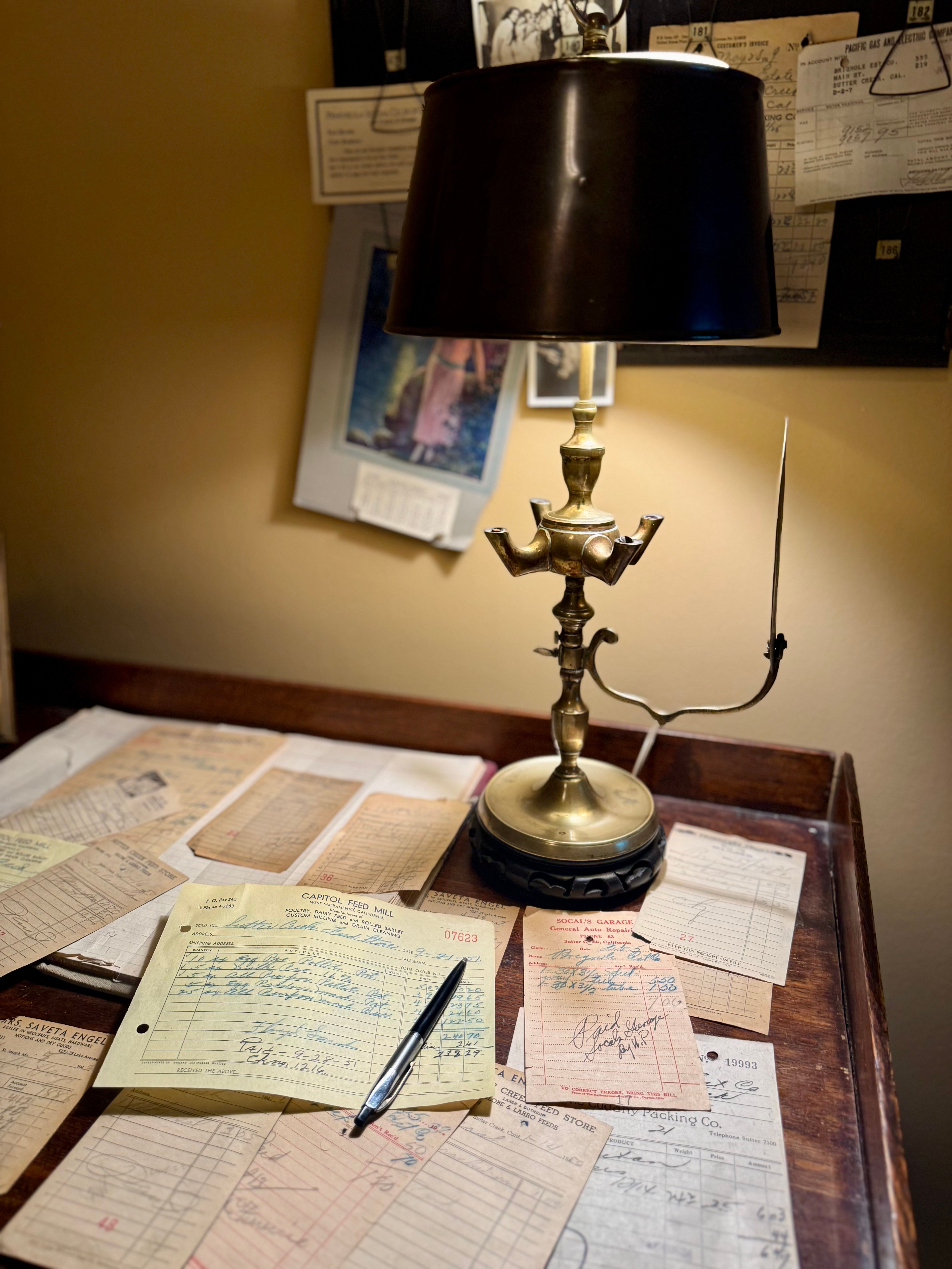 Vintage writing desk with a brass lamp, scattered papers, and a fountain pen in warm light, representing the local, welcoming character of a Fredericksburg law office.