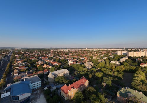 Aerial view of a sunny urban residential neighborhood with houses and greenery.