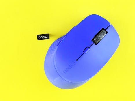 Bright blue wireless computer mouse on vibrant yellow backdrop, perfect for tech and design concepts.
