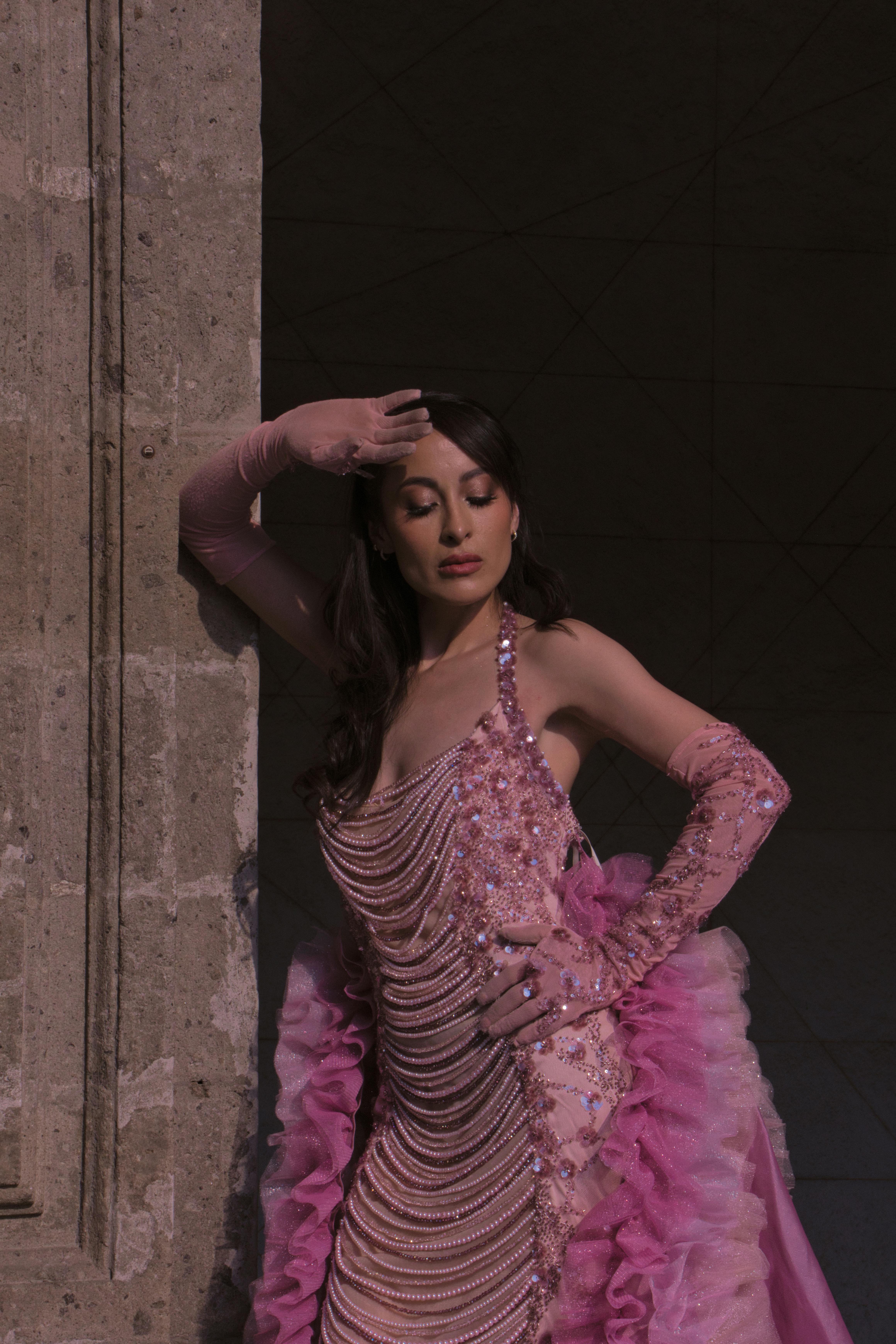 Free Elegant woman in a pink gown poses against a stone wall, exuding grace and sophistication. Stock Photo