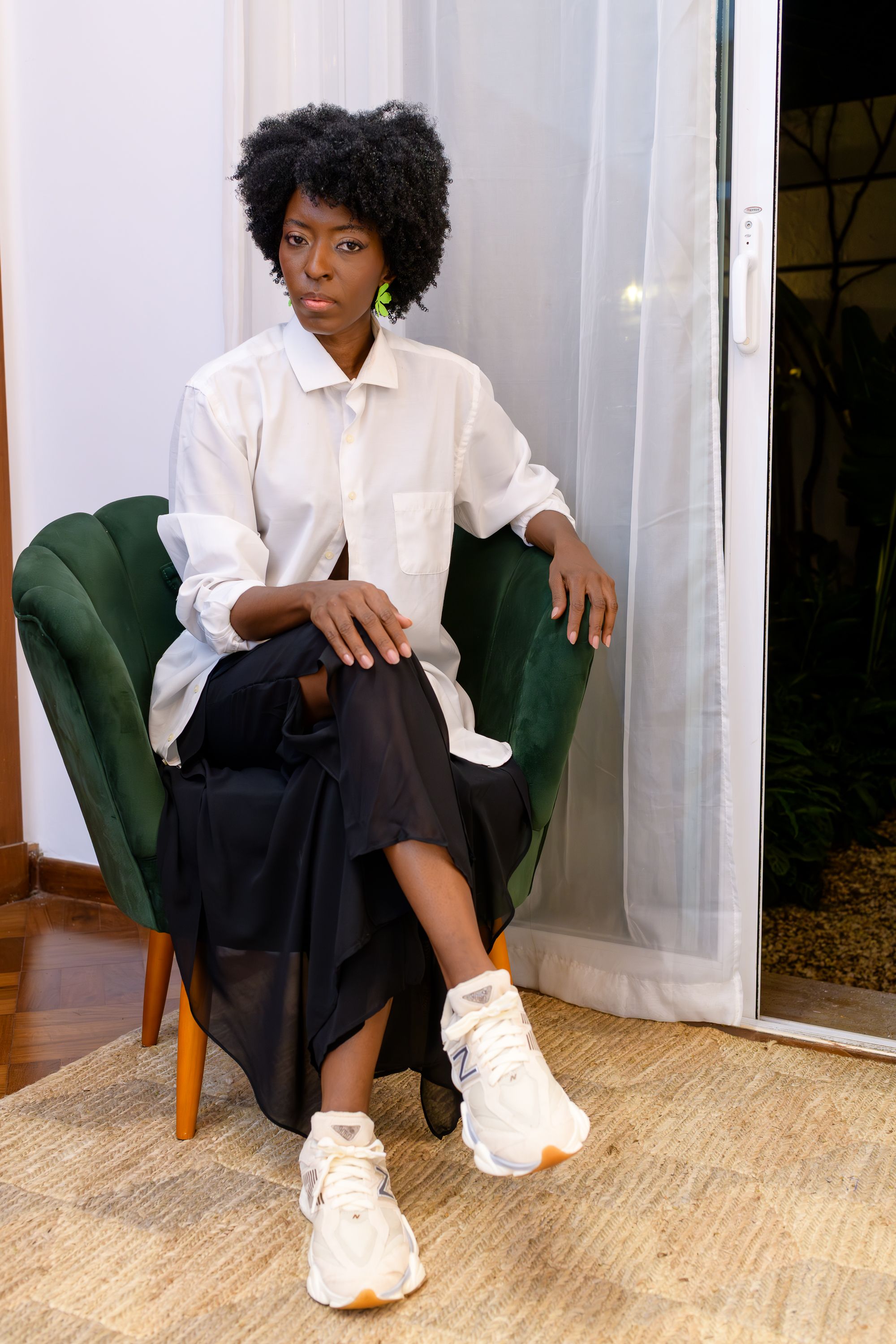 Mulher elegante em traje casual chique sentada em um ambiente interno em São Paulo, Brasil.