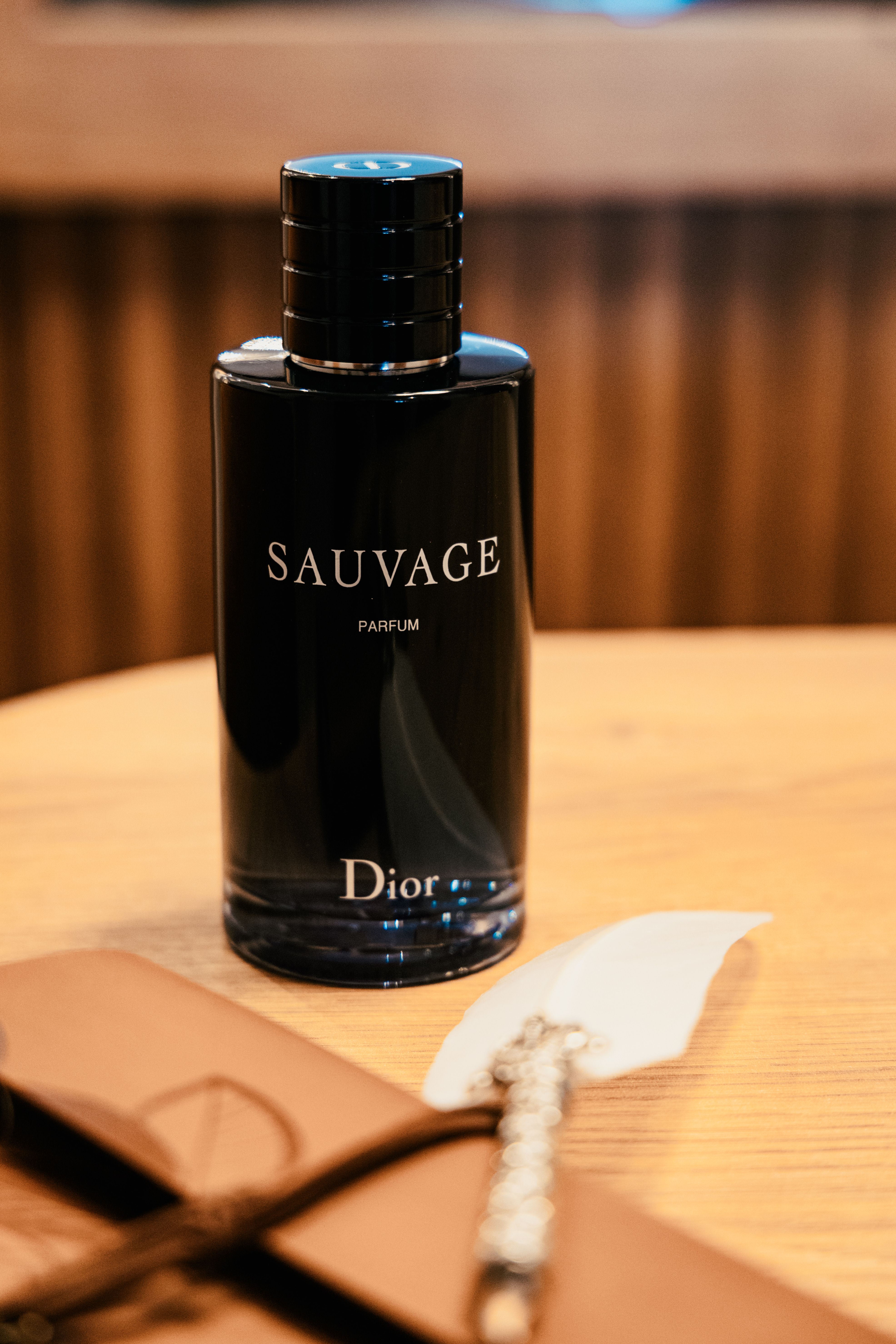 Sophisticated black perfume bottle 'Sauvage' elegantly displayed on a wooden table.