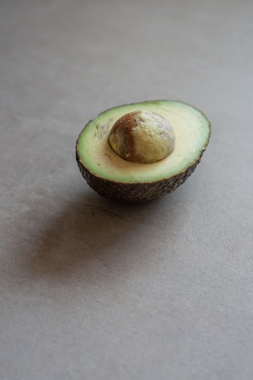 Free A ripe avocado half displayed on a neutral surface, ideal for food and health themes. Stock Photo