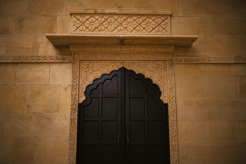 Free Ornately designed black wooden door set in a detailed sandstone wall showcasing cultural architecture. Stock Photo