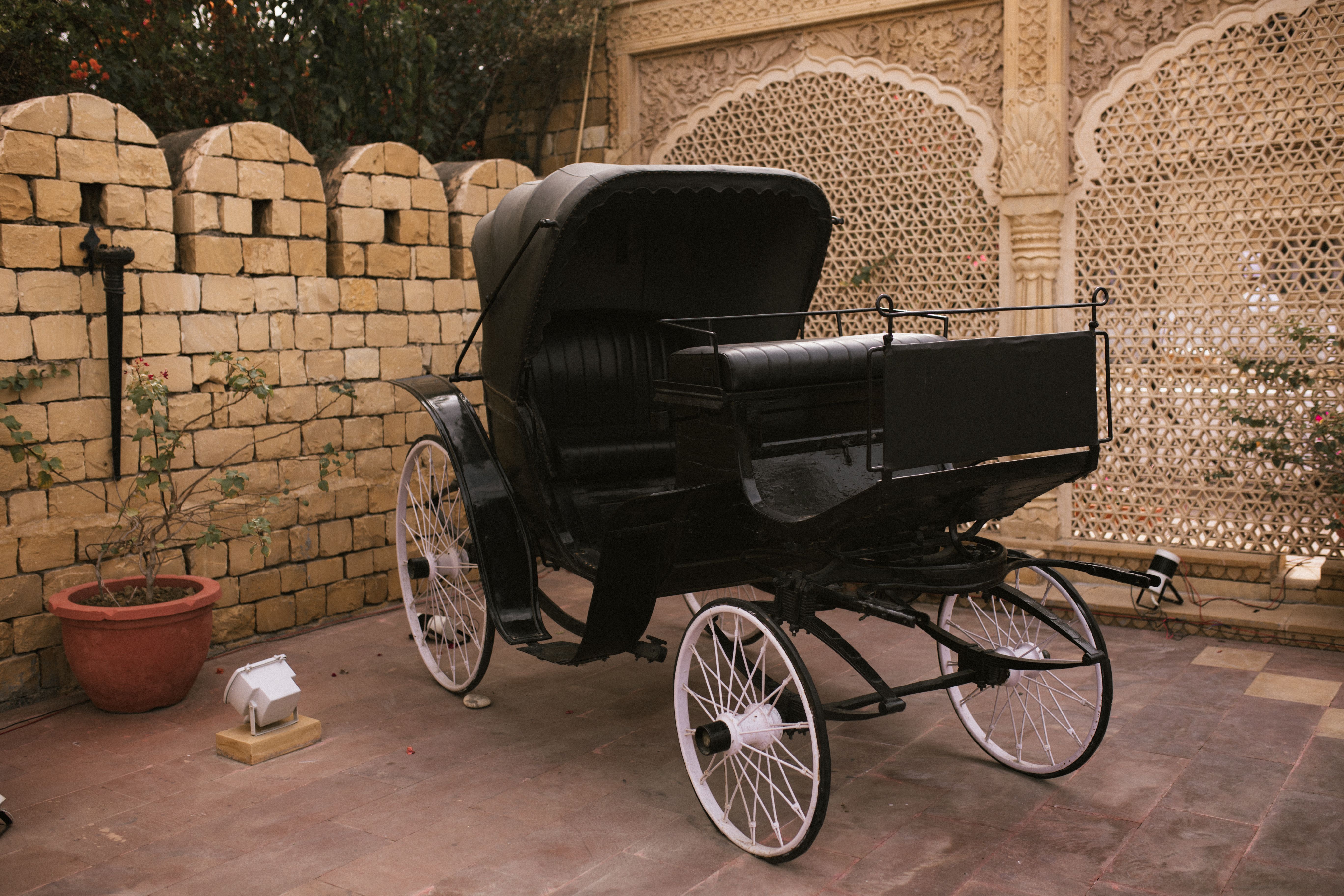Elegant black carriage in a historical courtyard setting against stone walls, perfect for travel or heritage themes.