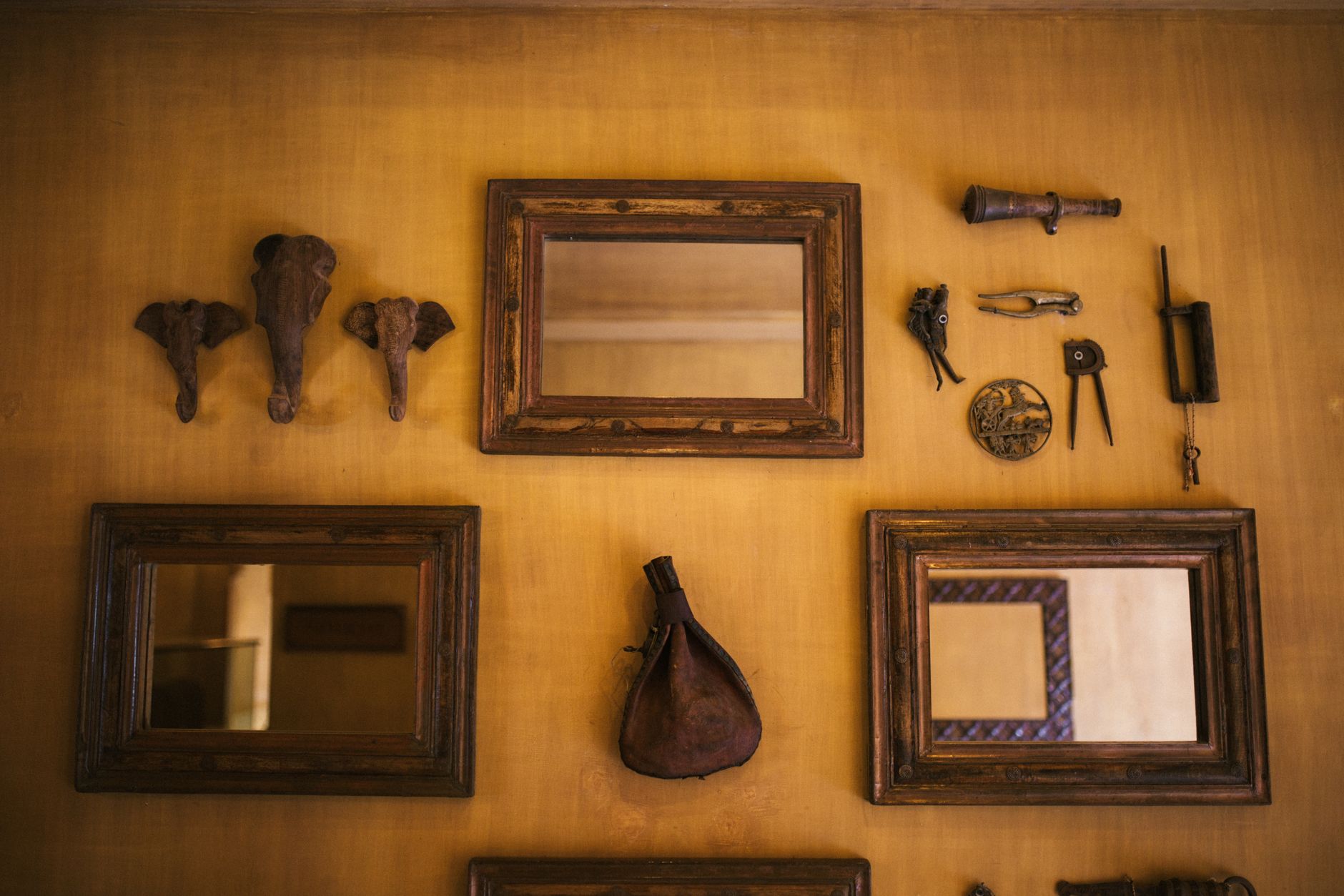 A collection of vintage mirrors and artifacts on a rustic wall, creating an artistic yet cozy ambiance.