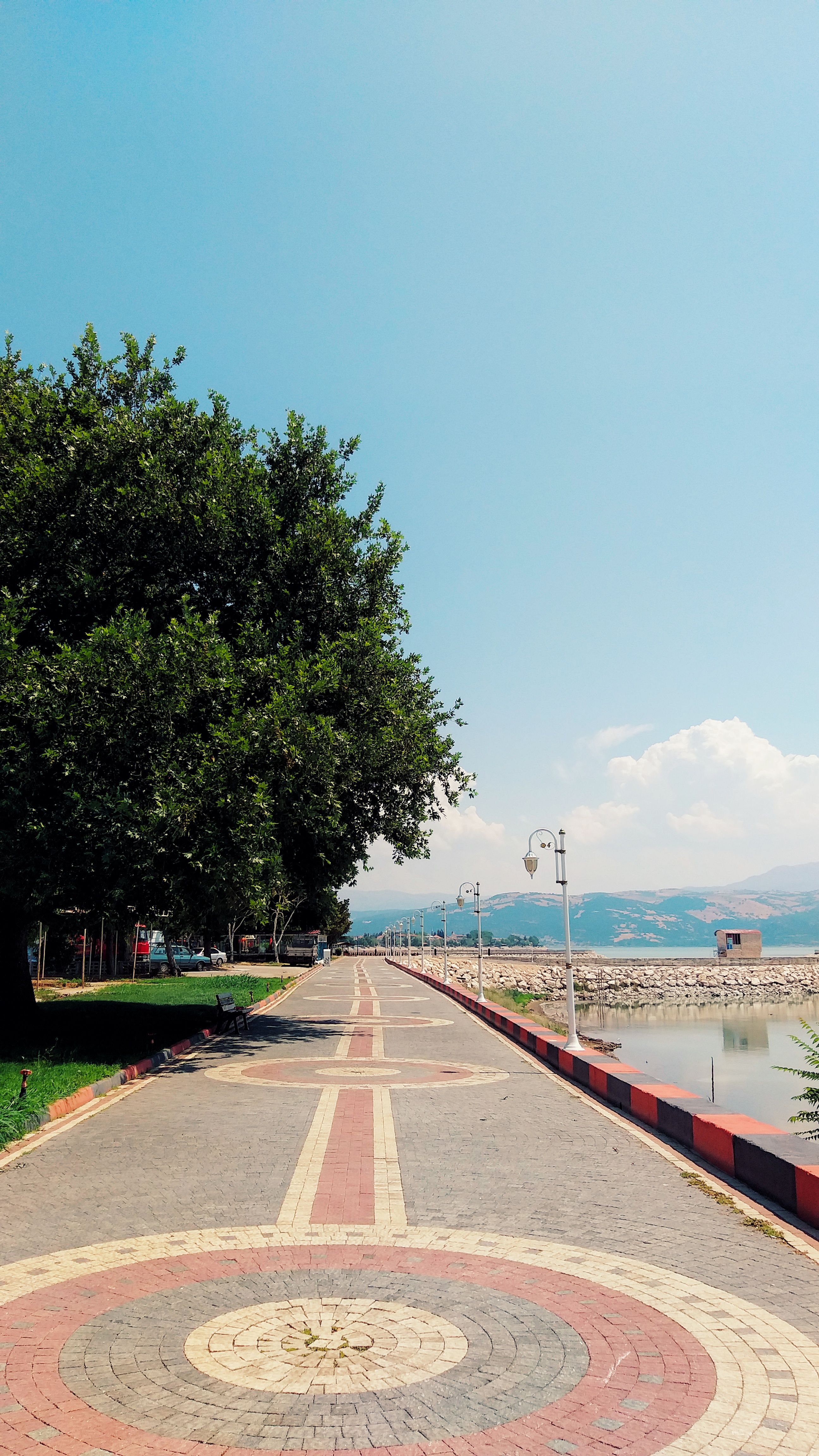 Beautiful summer view of the lakeside promenade in Eğirdir, Isparta, Türkiye, featuring clear blue skies and vibrant foliage.