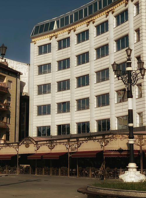 Free Elegant hotel building with outdoor cafe seating in Üsküp, North Macedonia, under a clear sky. Stock Photo