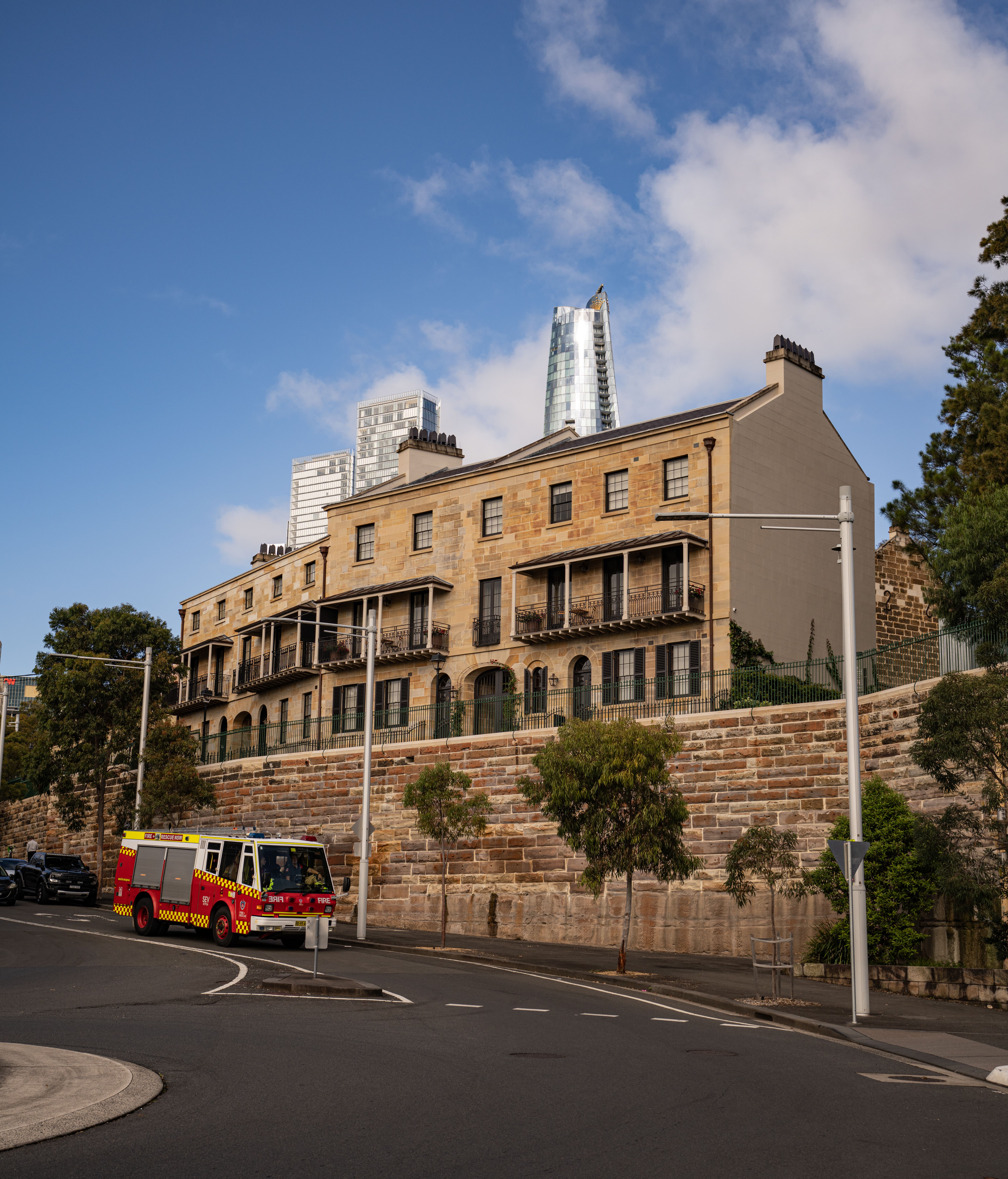 Charming historic building in Sydney with a modern skyline backdrop. Fire truck visible.
