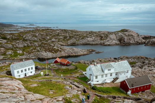 Dramatic landscape at Lindesnes Lighthouse, featuring traditional Norwegian houses on a rocky coast.