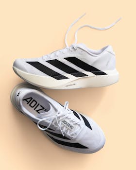 Modern white running shoes featuring black stripes on a neutral background.